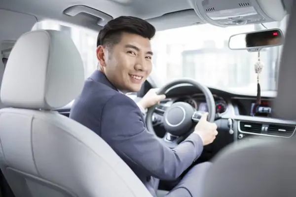 Confident Chinese businessman driving car